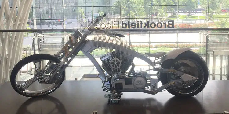 A chopper motocycle sitting on a display stand mounted on a biker bar.