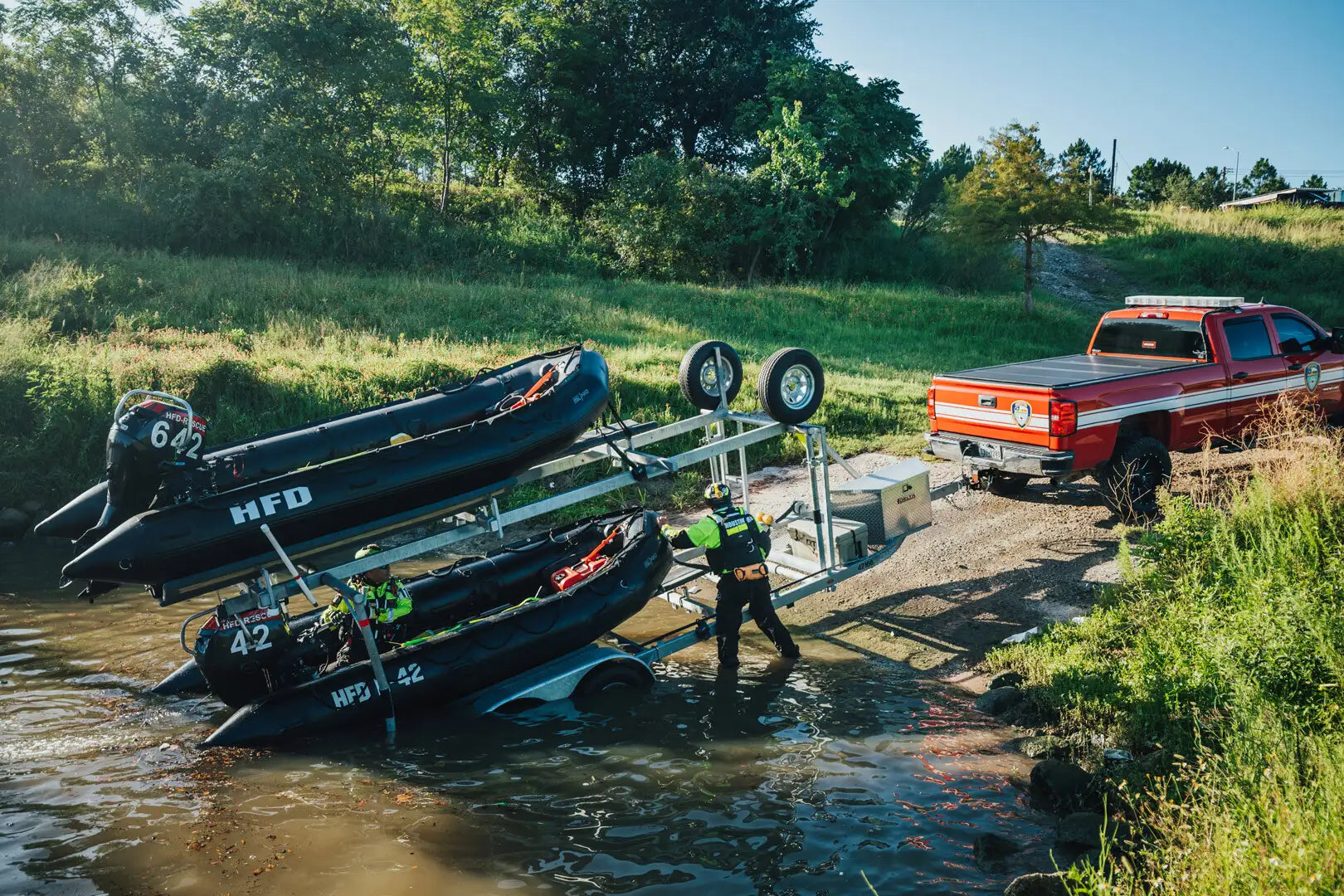 A water rescue team unloading rescue rafts from a trailer hooked to a red truck.