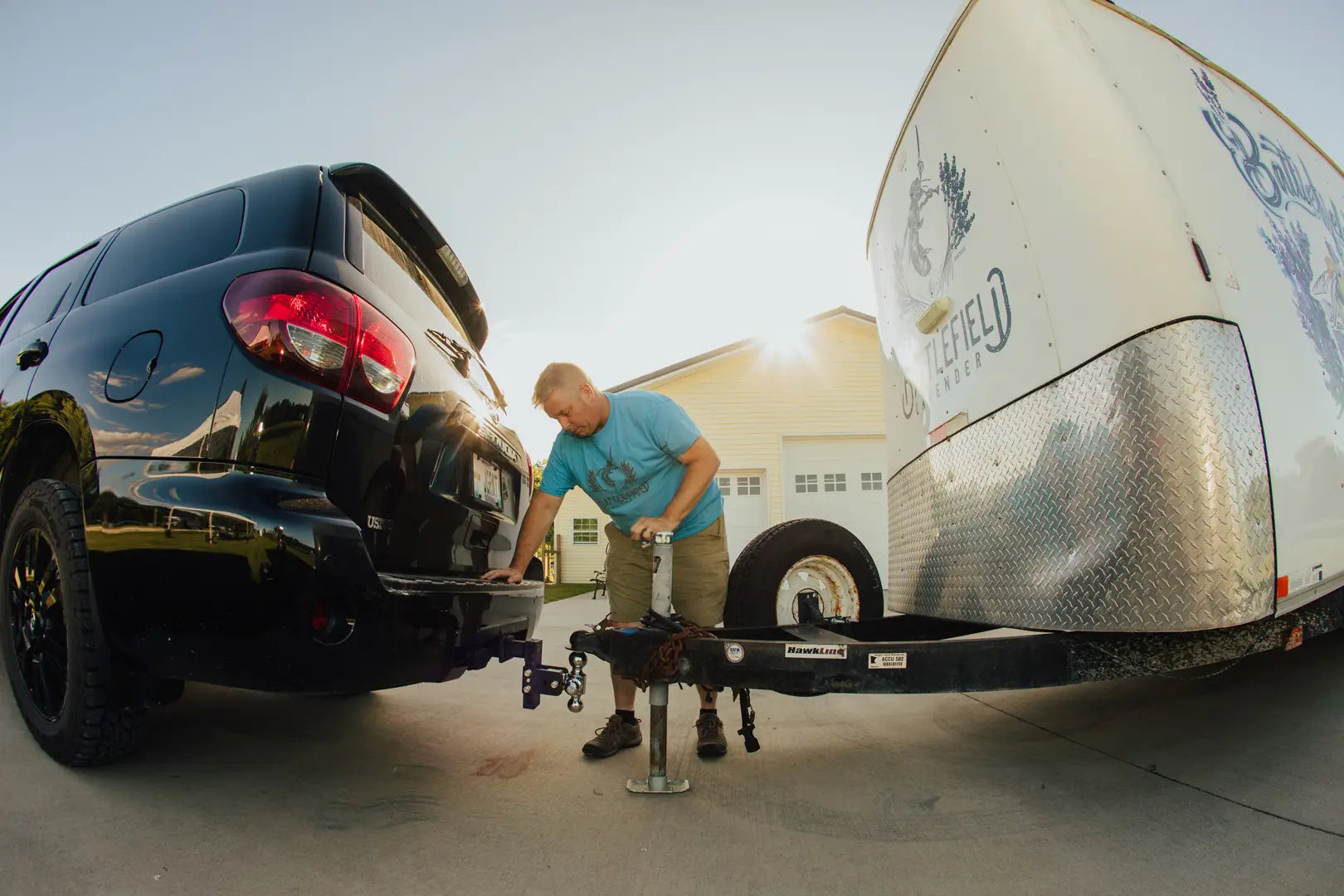 A man hitching a trailer to his Tow & Stow on the back of a black SUV.