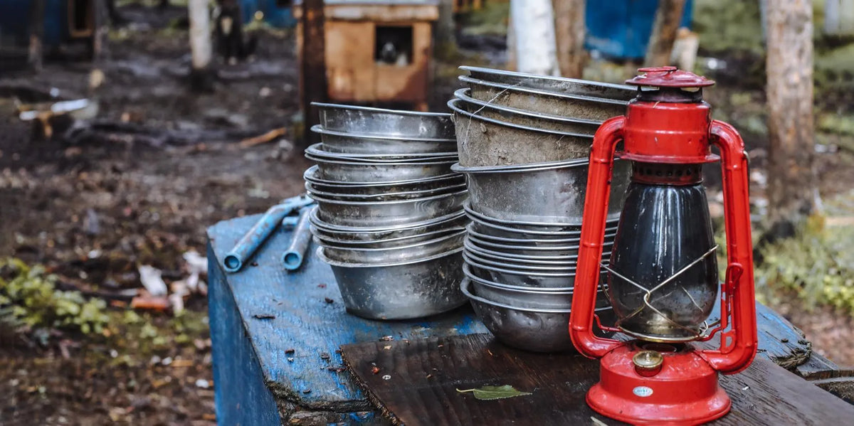 Stack of metal bowls and plates and a red lantern on a table outdoors.