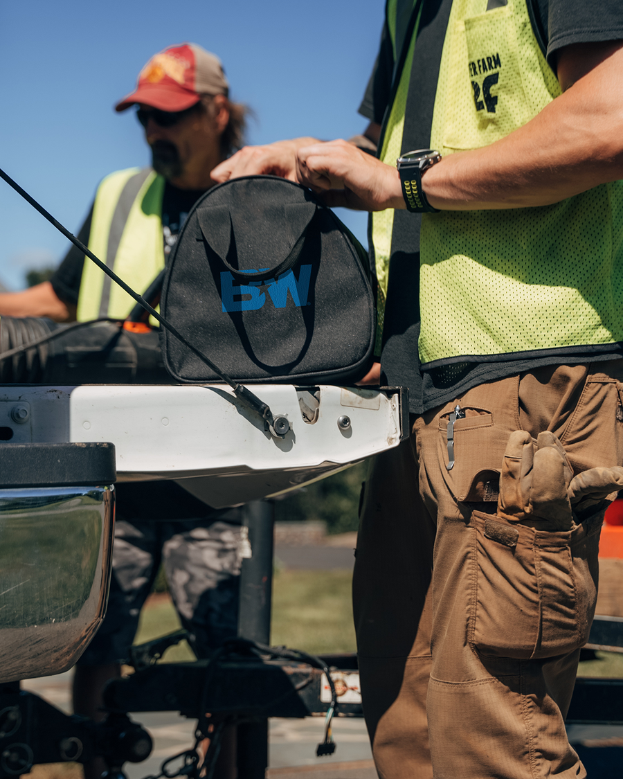 workers standing near the tailgate of a pickup with one holding a bag with a B&W logo to carry the ICON lock