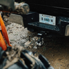 A close-up shot of the rear bumper of a pickup with a tow & stow drop hitch with a browning logo, attached to a trailer coupler, and a license plate reading B AND W.