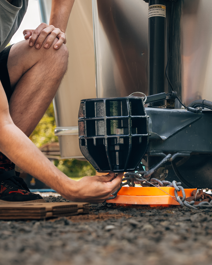 a person kneeling in front of a trailer coupler installing a B&W Icon Trailer Lock.