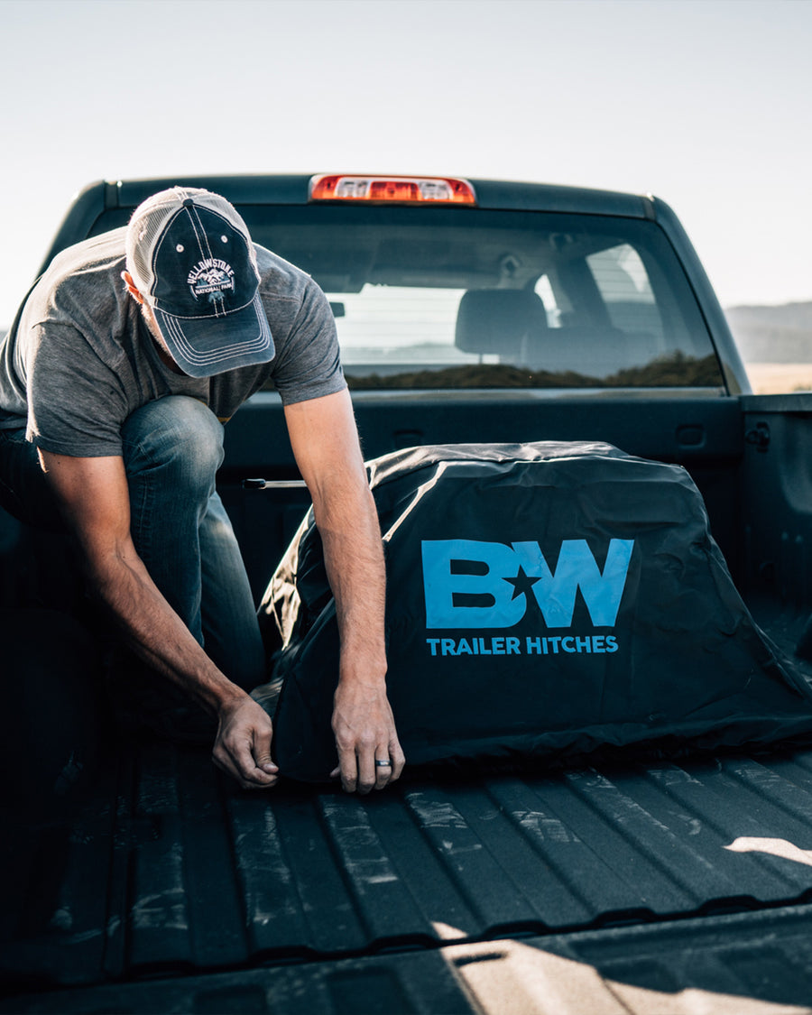 B&W Trailer Hitches Companion OEM fifth wheel hitch vinyl cover being installed in the bed of a pickup.