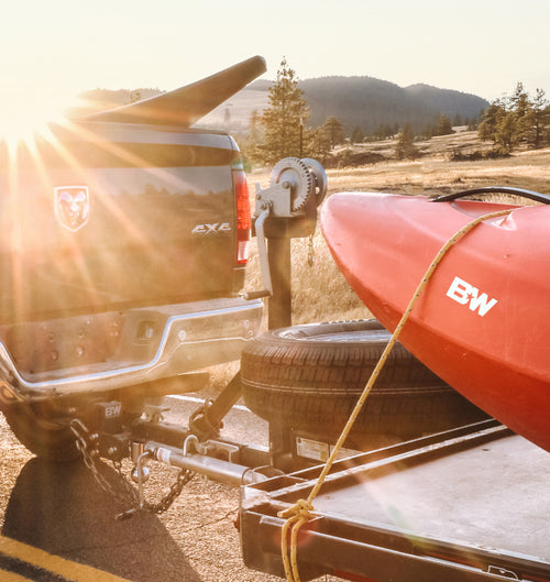 a pickup hauling a boat trailer connected with a B&W Tow & Stow Adjustable Ball Mount