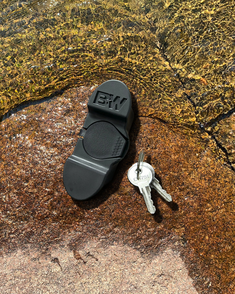 B&W Trailer Hitches dual pin lock with keys sitting on a river rock with water rippling