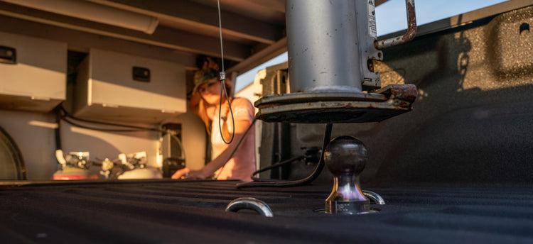 a gooseneck coupler being lowered onto a turnoverball gooseneck ball in the bed of a pickup truck